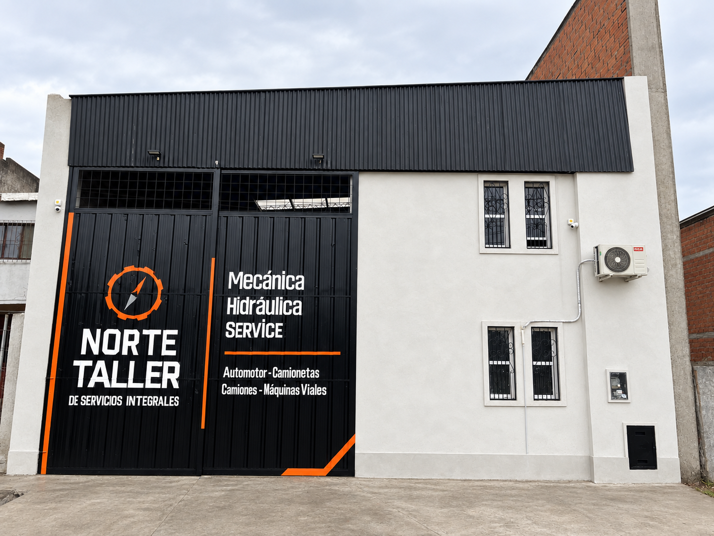 Frente de Norte Taller en Lincoln 518, San Miguel de Tucumán, con el portón pintado con el logo y los servicios Mecánica, Hidráulica y Service